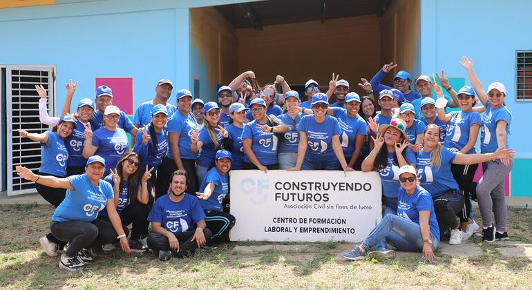 Trabajadores de Construyendo Futuros posan juntos frente a un centro de formación laboral y emprendimiento.